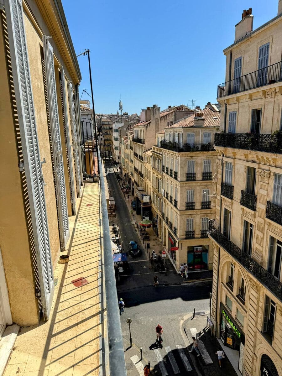Vue plongeante sur une rue marseillaise depuis un balcon, en plein soleil